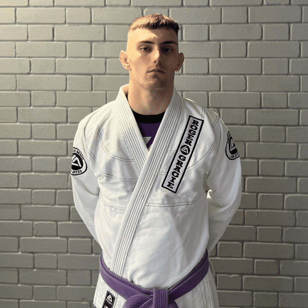 Purple belt male assistant coach smiling at the camera in his Gi.