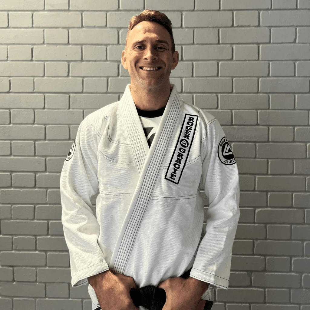 Black belt head coach and co-founder smiling at the camera in his Gi.